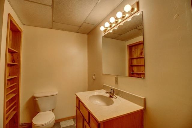 bathroom with vanity, a drop ceiling, and toilet