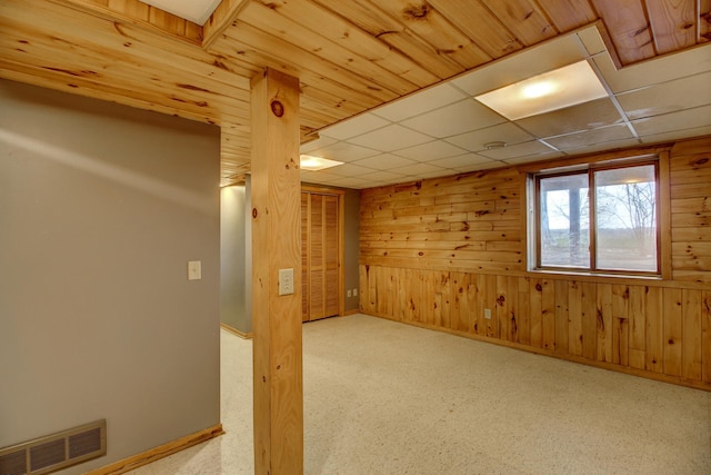 below grade area featuring wooden walls, baseboards, and visible vents