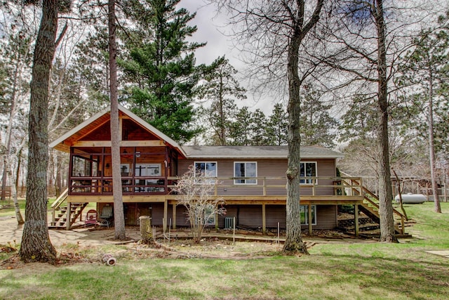 rear view of property featuring a lawn, a deck, and stairway