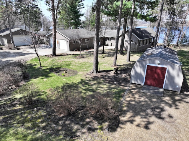 view of yard featuring a garage, a storage unit, an outdoor structure, and driveway