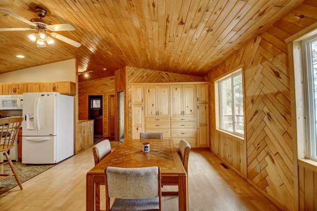 dining room with wooden walls, light wood-style flooring, a ceiling fan, vaulted ceiling, and wood ceiling