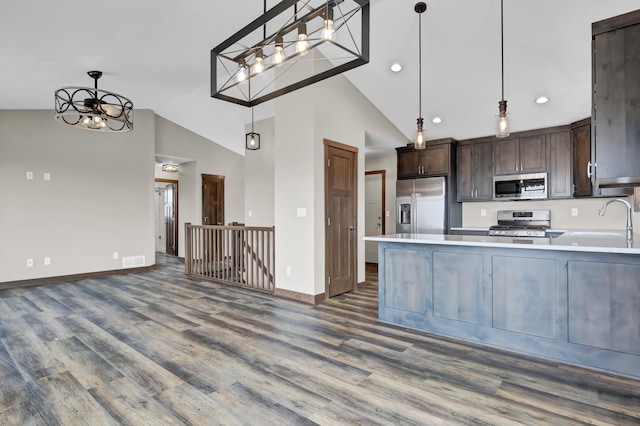 kitchen with a sink, appliances with stainless steel finishes, light countertops, and an inviting chandelier