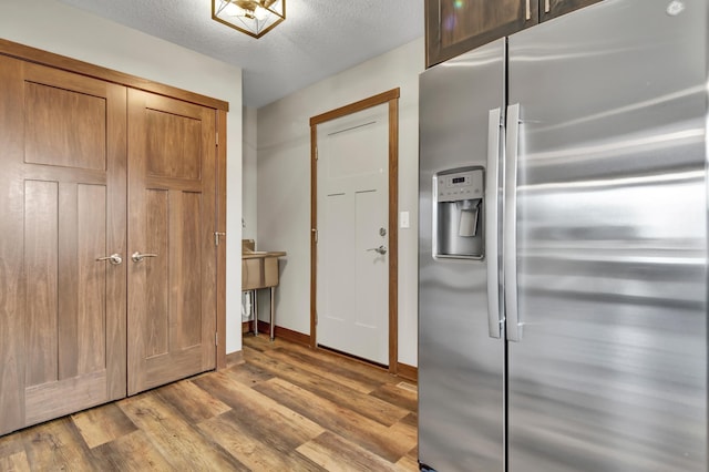 kitchen with baseboards, a textured ceiling, wood finished floors, and stainless steel refrigerator with ice dispenser