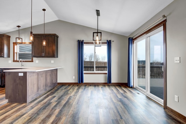 kitchen with dark brown cabinetry, light countertops, vaulted ceiling, a peninsula, and dark wood-style floors