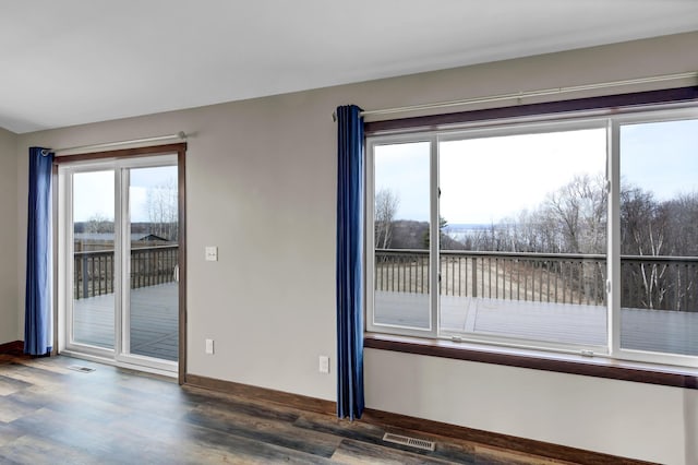 unfurnished room with wood finished floors, visible vents, and baseboards