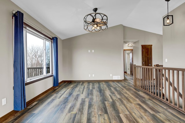 empty room with a chandelier, lofted ceiling, baseboards, and wood finished floors