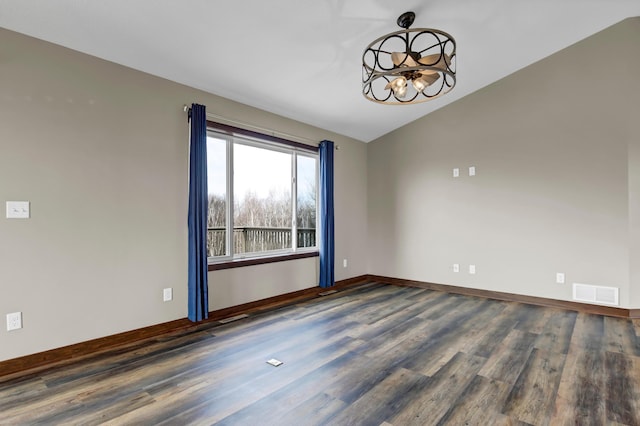 empty room featuring wood finished floors, baseboards, visible vents, vaulted ceiling, and a chandelier