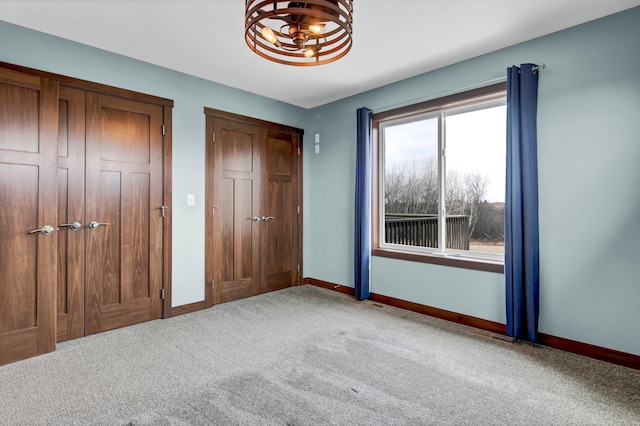 unfurnished bedroom featuring a chandelier, baseboards, and carpet