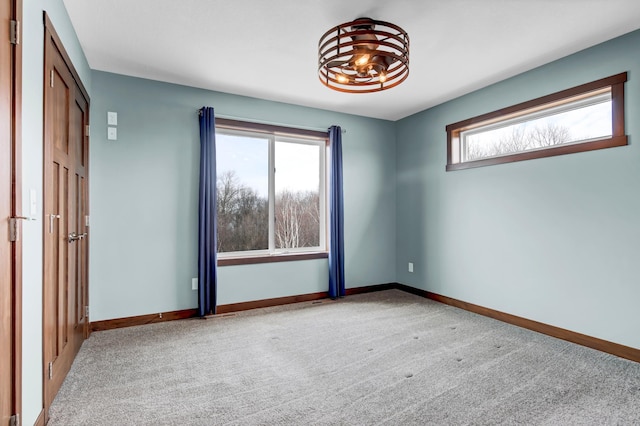 empty room featuring an inviting chandelier, baseboards, and carpet floors