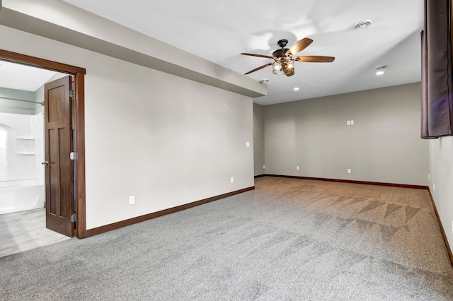 carpeted spare room featuring baseboards and a ceiling fan