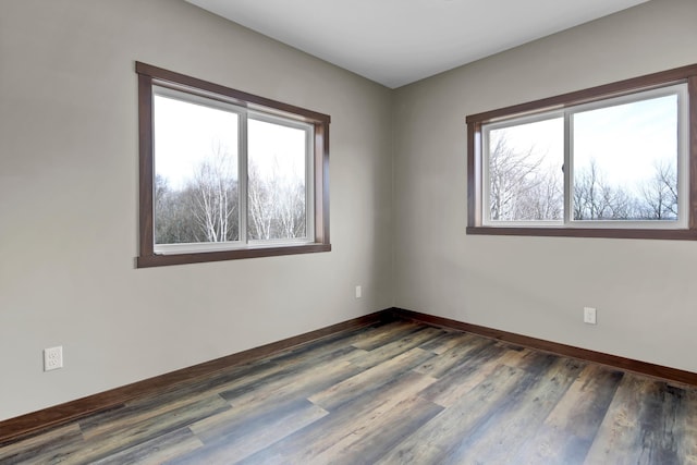spare room featuring baseboards and dark wood-style flooring