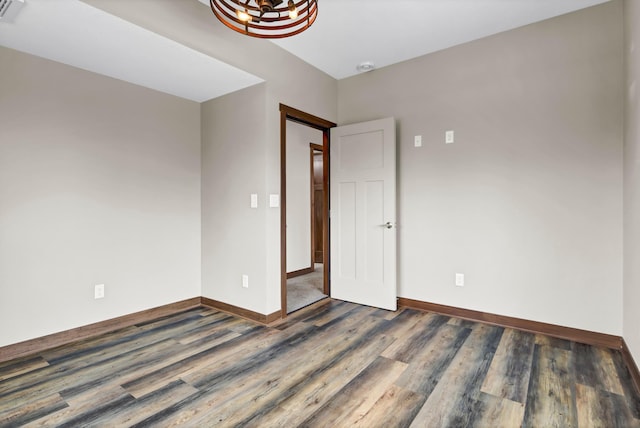 spare room with visible vents, baseboards, and dark wood-type flooring