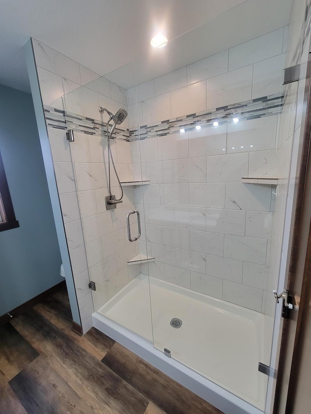 full bathroom featuring wood finished floors and a shower stall