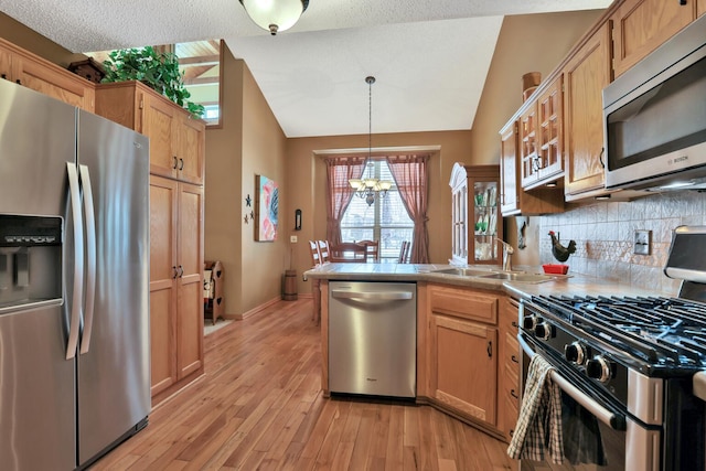 29561 Mentzer Ct, Lindstrom, MN 55045 - kitchen featuring stainless steel appliances, a peninsula, a chandelier, light wood-style flooring, and vaulted ceiling