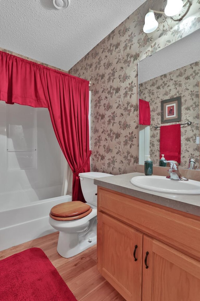 29561 Mentzer Ct, Lindstrom, MN 55045 - bathroom featuring wallpapered walls, a textured ceiling, wood finished floors, toilet, and vanity