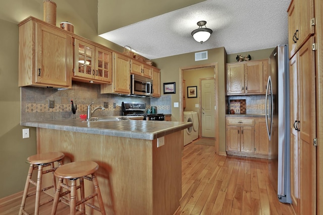 29561 Mentzer Ct, Lindstrom, MN 55045 - kitchen with a peninsula, stainless steel appliances, a sink, a breakfast bar, and backsplash