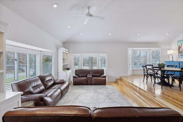 living room with plenty of natural light, light wood-style flooring, a ceiling fan, and vaulted ceiling