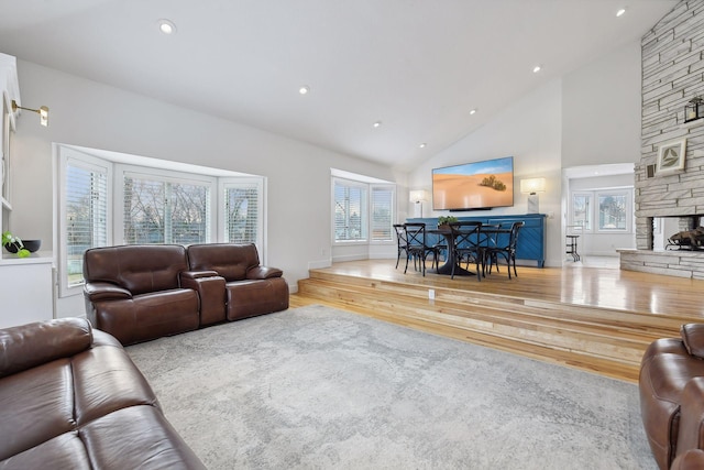 living area featuring high vaulted ceiling, wood finished floors, recessed lighting, a fireplace, and baseboards