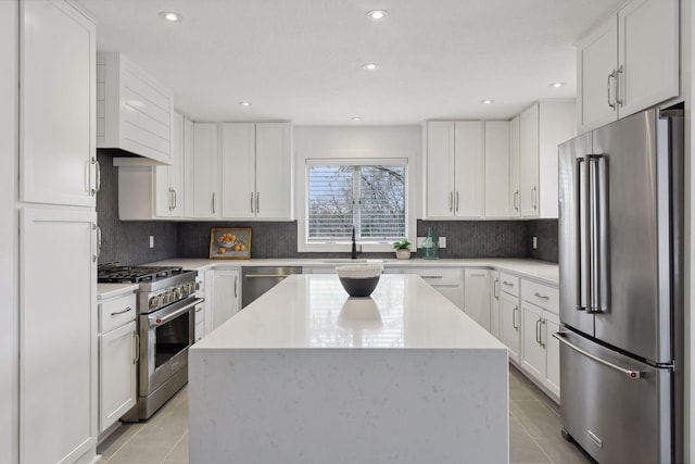kitchen with light tile patterned floors, white cabinets, appliances with stainless steel finishes, and a center island