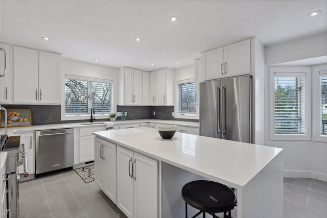 kitchen featuring a sink, a wealth of natural light, appliances with stainless steel finishes, and light tile patterned flooring