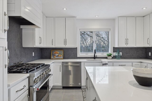 kitchen with tasteful backsplash, light tile patterned floors, stainless steel appliances, and light countertops