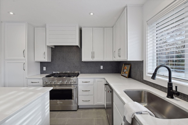 kitchen featuring white cabinets, premium range hood, appliances with stainless steel finishes, and a sink