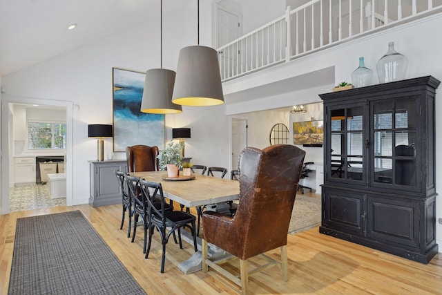 dining space with light wood finished floors and high vaulted ceiling