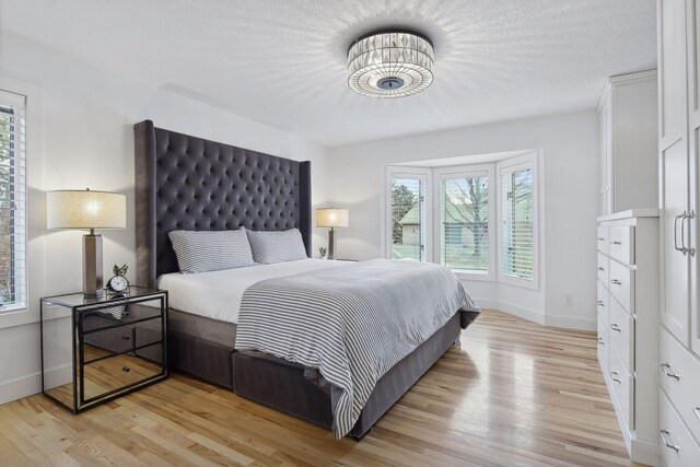 bedroom with light wood-style flooring, a textured ceiling, and baseboards