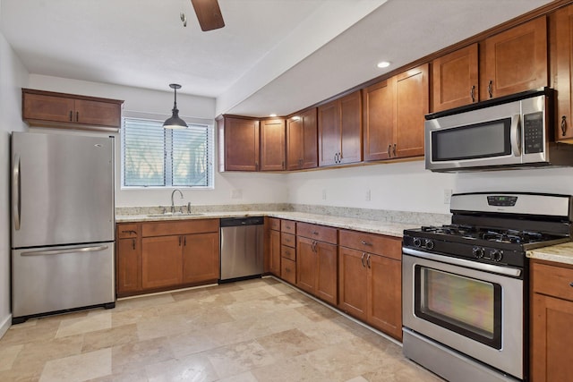 kitchen featuring a sink, stainless steel appliances, brown cabinetry, and hanging light fixtures