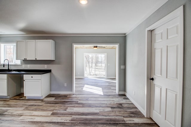 33916 Twin Oaks Loop, Motley, MN 56466 - kitchen with light wood-style floors, baseboards, dark countertops, white cabinetry, and ceiling fan