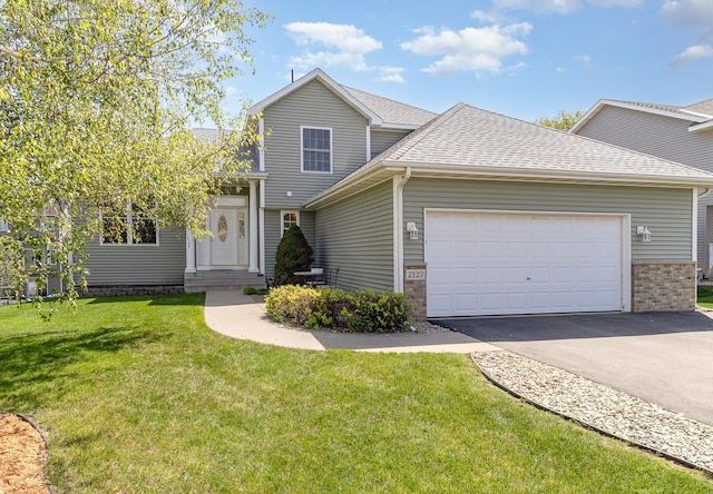 traditional home with a garage, roof with shingles, a front yard, asphalt driveway, and brick siding