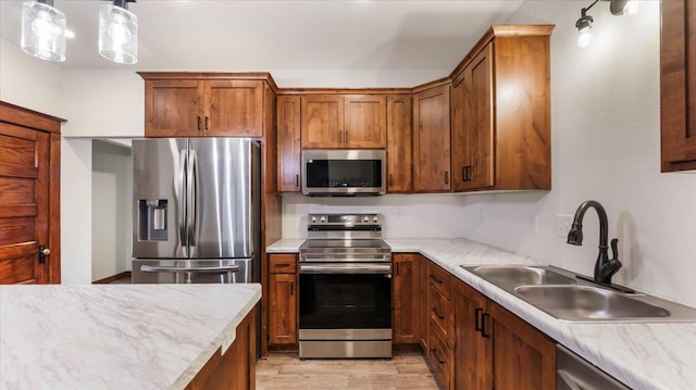 741 Riverside Rd, Holdingford, MN 56340 - kitchen featuring stainless steel appliances, a sink, light wood-type flooring, and brown cabinetry
