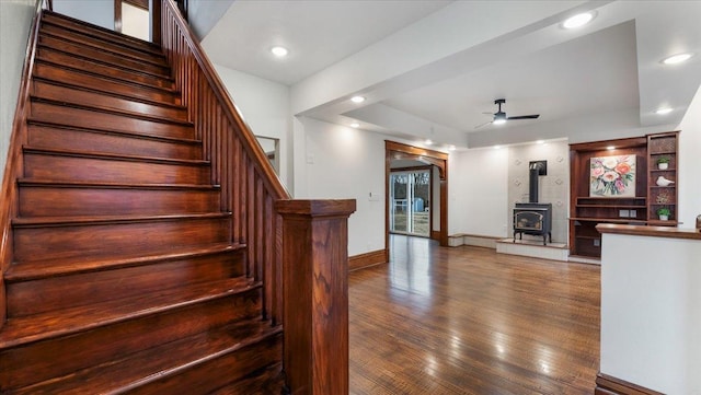 741 Riverside Rd, Holdingford, MN 56340 - stairs featuring ceiling fan, a wood stove, a tray ceiling, hardwood / wood-style flooring, and baseboards