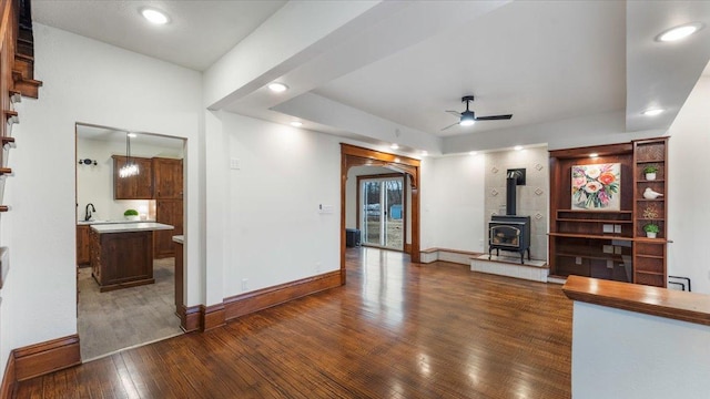 741 Riverside Rd, Holdingford, MN 56340 - unfurnished living room with dark wood-style flooring, a wood stove, a ceiling fan, baseboards, and recessed lighting