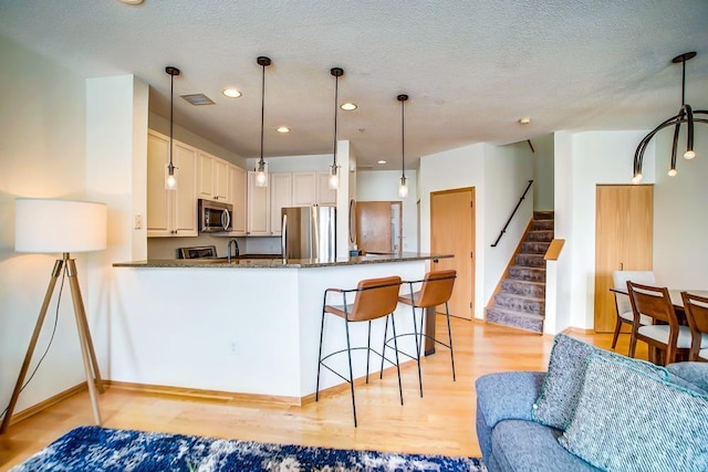 500 2nd St Unit 102, Minneapolis, MN 55401 - kitchen with light wood finished floors, a peninsula, a breakfast bar, stainless steel appliances, and recessed lighting