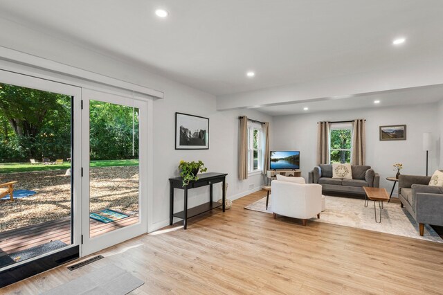 living room featuring baseboards, light wood finished floors, recessed lighting, and visible vents