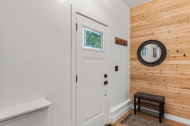 doorway to outside featuring baseboards, wood walls, and wood finished floors