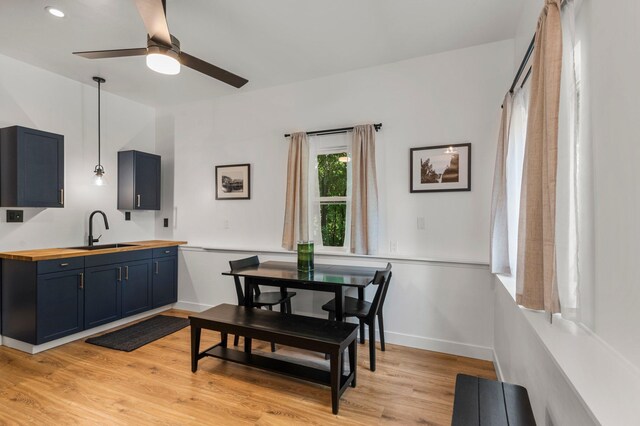 dining room with a ceiling fan, baseboards, and light wood-style flooring