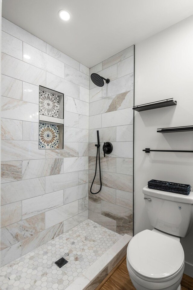 bathroom featuring recessed lighting, toilet, tiled shower, and wood finished floors