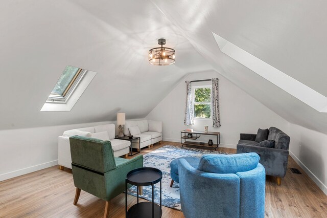 living room with baseboards, visible vents, lofted ceiling with skylight, and light wood-style floors