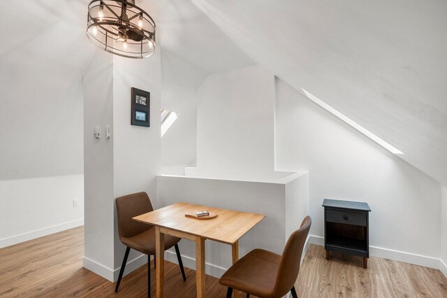 dining area with baseboards, vaulted ceiling, and wood finished floors