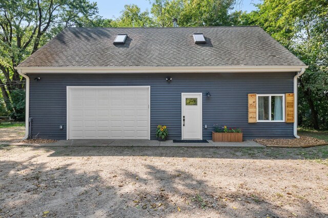 view of front of house with roof with shingles and a detached garage