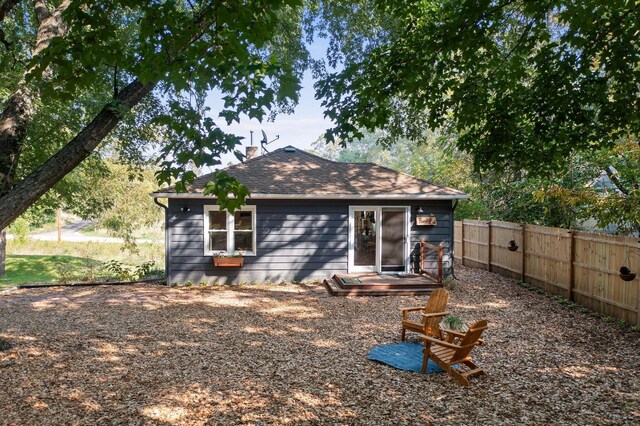 rear view of property with fence, a chimney, and roof with shingles