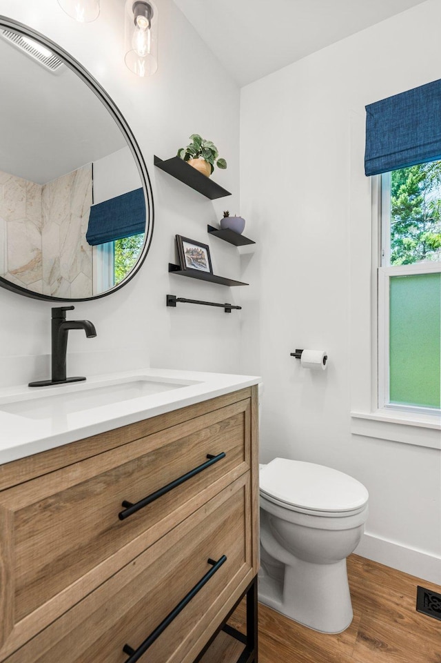 bathroom with toilet, visible vents, wood finished floors, and vanity