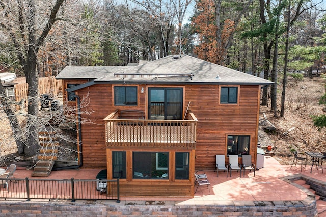back of house featuring a shingled roof, a balcony, and a patio