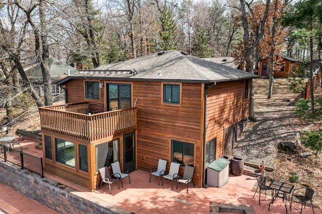 back of property with an attached garage, a shingled roof, a patio, and a balcony