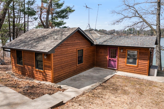 chalet / cabin with a patio and a shingled roof