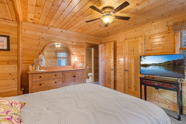 bedroom with wooden walls, ensuite bath, wood ceiling, and ceiling fan