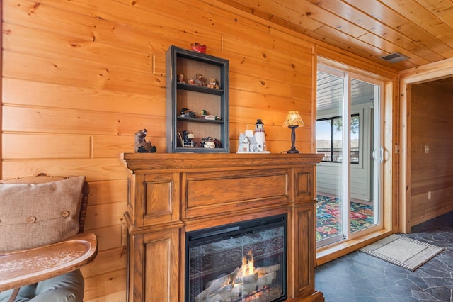 room details featuring a warm lit fireplace, visible vents, wood walls, and wooden ceiling