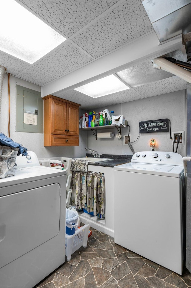 washroom featuring electric panel, independent washer and dryer, and cabinet space